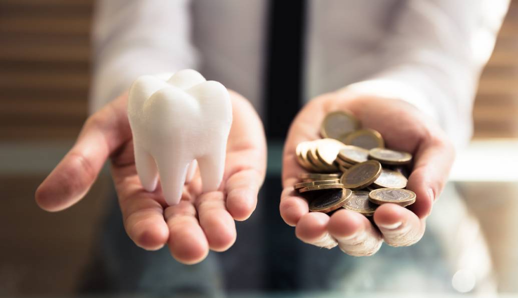 Person holds a tooth in one hand and pound coins in the other